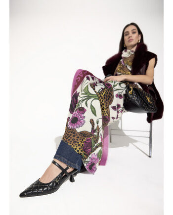 Zapatos negros de puntera fina con tachas Lola Casademunt combinados con pantalón estampado.