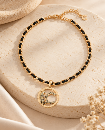 Collar corto Lola Casademunt dorado con detalles negros, cadena trenzada y medallón circular con logotipo animal texturizado.