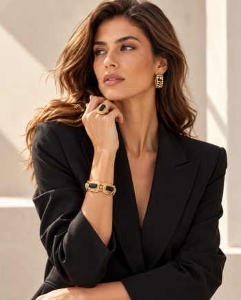 Modelo con pulsera elástica Lola Casademunt de medallones acrílicos negros y dorados, combinada con americana negra