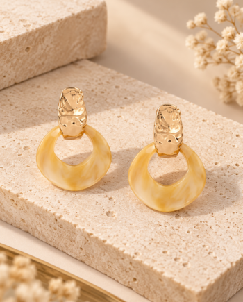 Pendientes Lola Casademunt de resina marmolada en tonos beige y dorados, con pieza superior metálica texturizada y colgante de aro irregular.