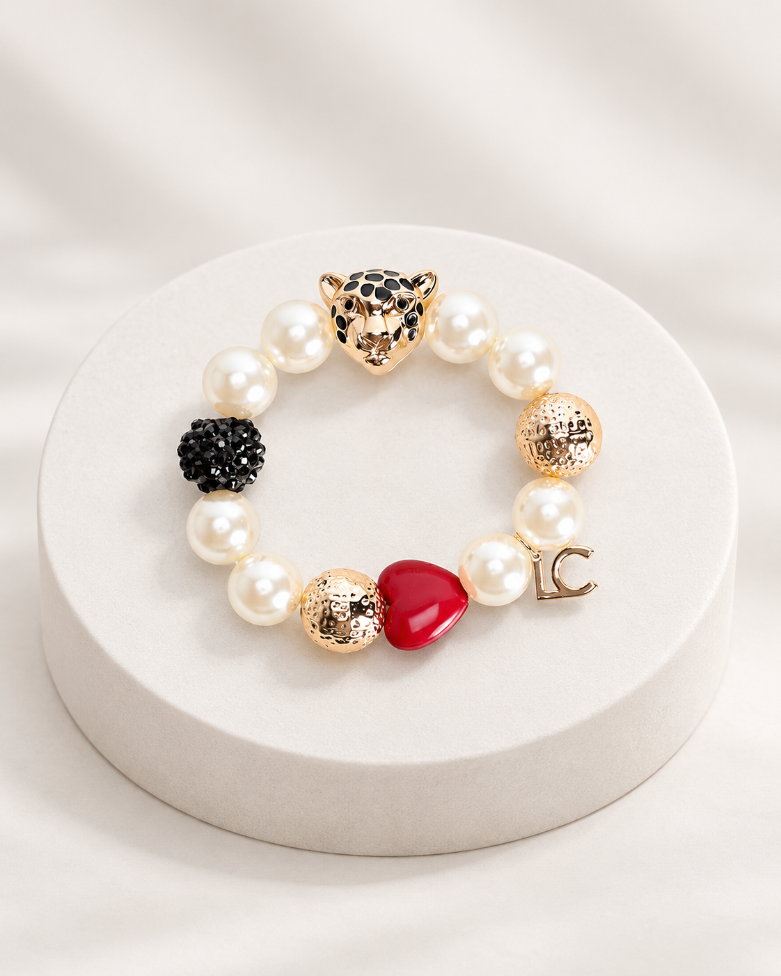 Pulsera Lola Casademunt perlas y charms blanco multicolor - vista principal Pulsera Lola Casademunt de perlas blancas con charms dorados, cabeza de felino, corazón rojo y detalle LC