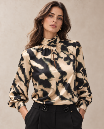 Modelo con blusa Lola Casademunt print mármol negro y crudo, cuello alto y mangas largas abullonadas, combinada con pantalón negro