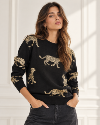 Modelo con jersey Lola Casademunt negro de manga larga, decorado con leopardos jacquard en tonos dorados y marrones y detalle de cadena dorada.
