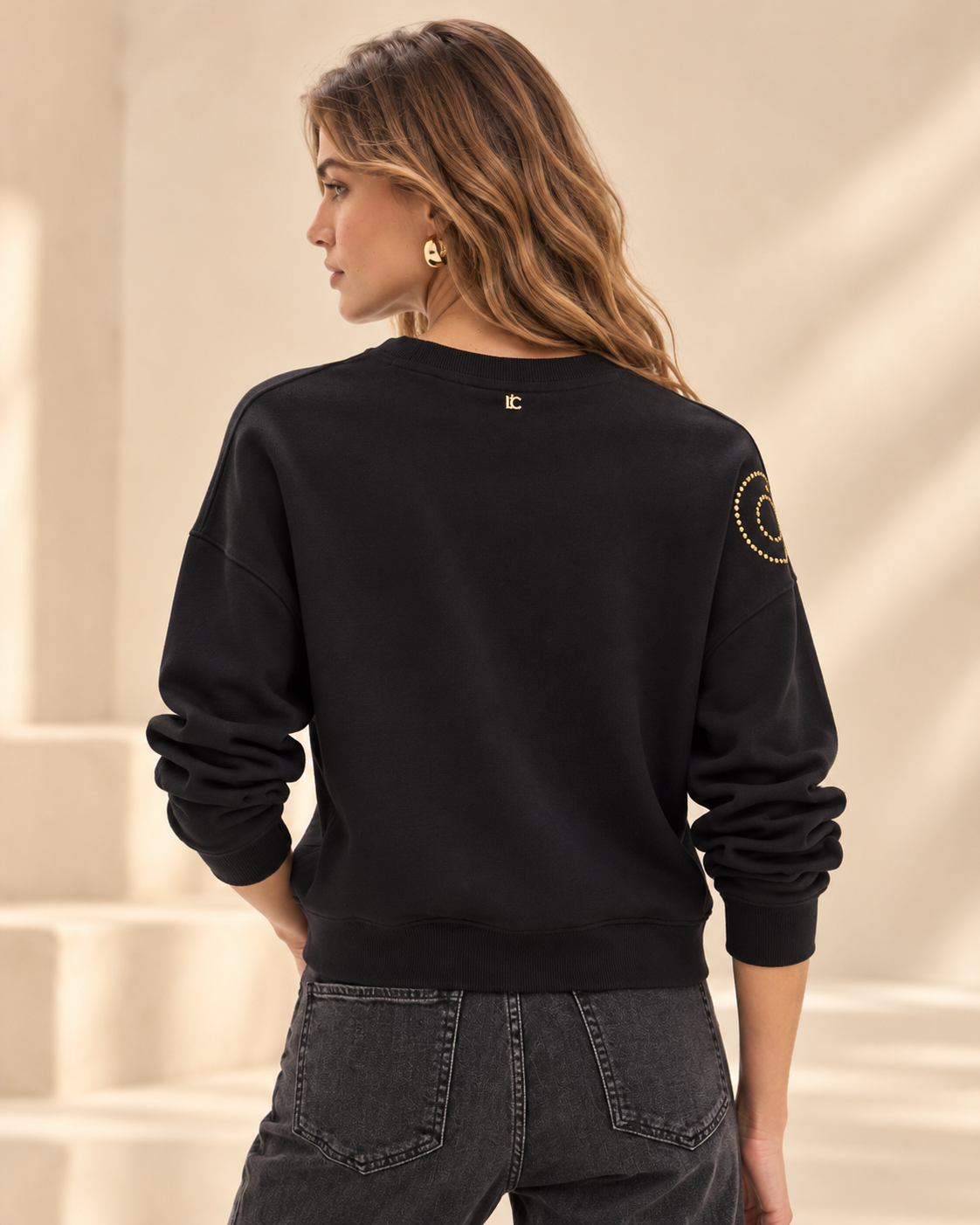 Sudadera Lola Casademunt negra leopardo dorado – vista trasera Vista trasera de la sudadera Lola Casademunt negra de manga larga y cuello redondo, con espalda lisa y acabado ajustado en el bajo.