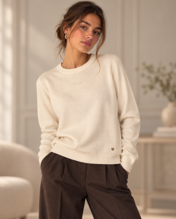 Modelo con camiseta Morgan Jacky marfil de cuello redondo y manga larga, combinada con pantalones marrón chocolate.