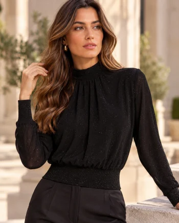Modelo con camiseta Morgan Toscar negra de cuello alto fruncido, manga larga y delicados detalles de strass, combinada con pantalones negros de vestir.